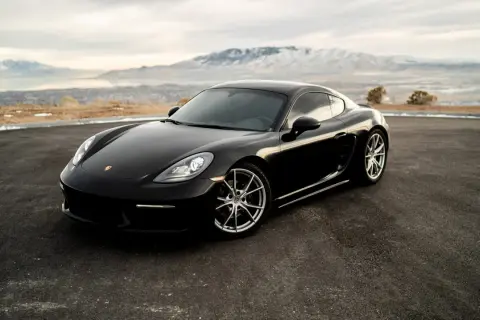 Czarny Porsche GTS na tle gór i jeziora.