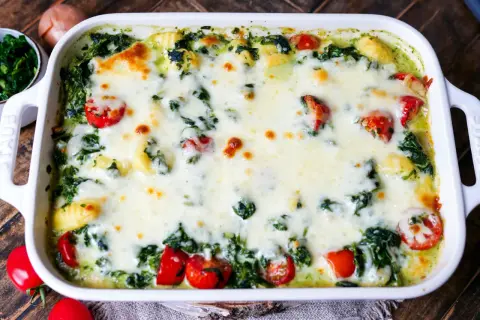 Gnocchi Spinat Auflauf mit geschmolzenem Käse und Kirschtomaten, ein köstliches Gericht, das zum Genießen einlädt.
