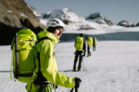 Bergsteiger mit leuchtend gelber Ausrüstung und Rucksäcken auf einer Gletscherwanderung. Die Packliste für die Hochtour ist komplett.