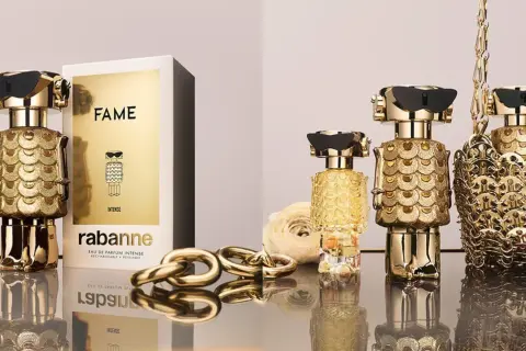 Złote flakony perfum FAME od Rabanne, ozdobione łuskami, przyciągają wzrok. Luksusowy dodatek dla każdej kobiety.