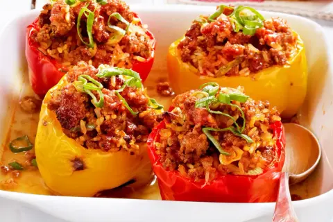 Gefüllte Paprika mit Hackfleisch und Reis, garniert mit Frühlingszwiebeln, in einer Auflaufform.