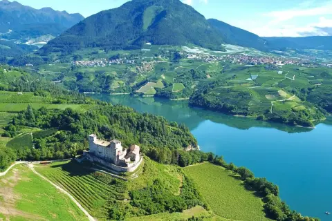 Castello di Thun domina il lago e i vigneti del Val di Non. Un paesaggio incantevole da esplorare, tra storia e natura.