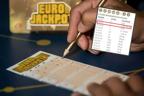 Ręka z ołówkiem nad kuponem Eurojackpot. Czy można grać w Eurojackpot za granicą? Wyniki pokazują wygrane w Polsce.