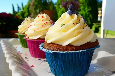 Tre cupcakes med fluffig frosting, dekorerade med strössel och lavendel. Perfekt frosting till cupcakes för en solig dag.
