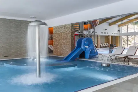 Relaks w hotelu w Szklarskiej Porębie z aquaparkiem: basen, zjeżdżalnia w kształcie słonia, wodospad i leżaki.
