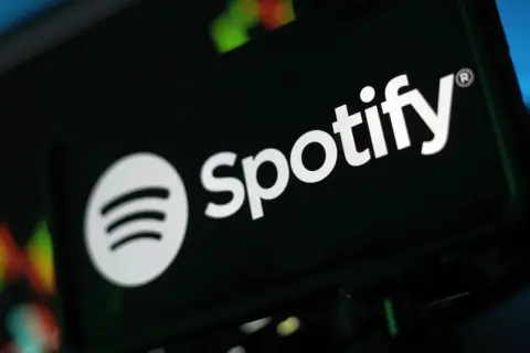 Logo Spotify na ciemnym tle, z rozmytymi kolorowymi światłami w tle.