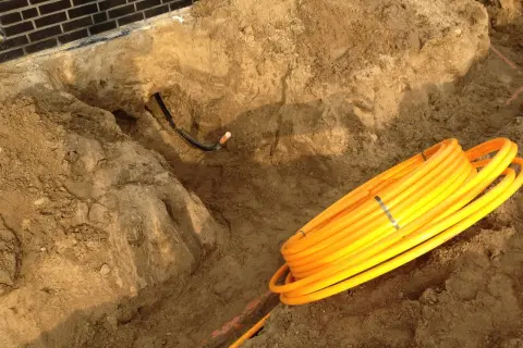 Baustelle: gelbe Rohre liegen bereit für die Gasleitung verlegen im Erdreich. Ein Graben ist ausgehoben.