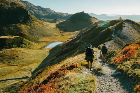 Deux randonneurs explorent un sentier de montagne pittoresque, profitant des couleurs d'automne et des paysages magnifiques. Les fiz sont en pleine aventure.
