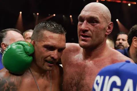 Två boxare, en med blod i ansiktet, omfamnar varandra. Tyson Fury vikt är en viktig faktor i deras matcher.