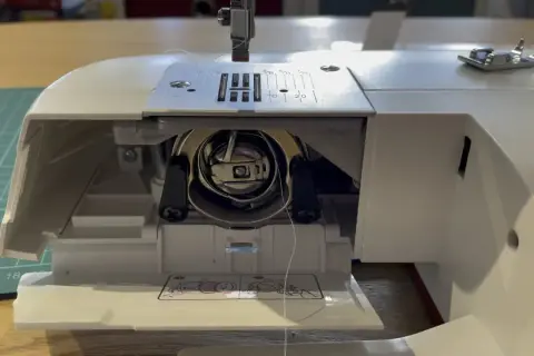 Zablokowane koło w maszynie do szycia. Widać mechanizm bębenka i igłę.