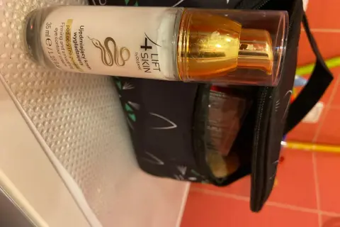 Krem pod oczy 4 Lift Skin ujędrnia i wygładza skórę. Złota pompka i czarna kosmetyczka z kocimi uszami.