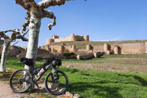 Bicicleta de montaña lista para rutas en bici por Soria, con un castillo medieval al fondo.