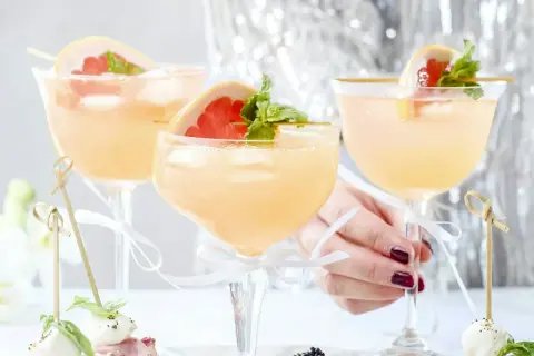 Tre eleganta glas med rosa drinkar, garnerade med grapefrukt och mynta. Perfekt drink till nyår!