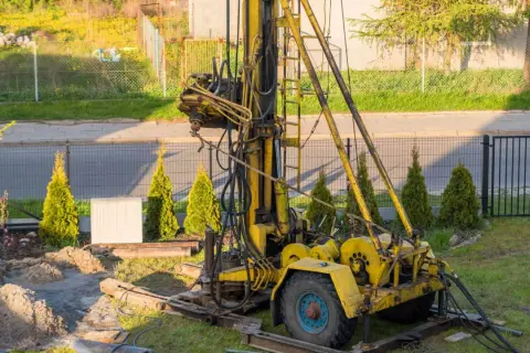 Żółta wiertnica na podwórku, gotowa do pracy. Zastanawiasz się nad studnia głębinowa koszt?