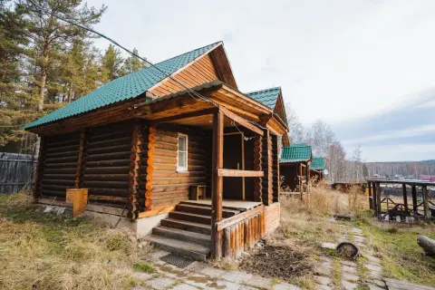 Solidny fundament pod domek letniskowy z bali, z zielonym dachem i drewnianą werandą.