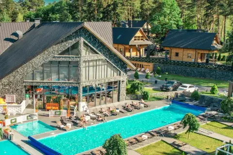 Hotel Bacówka Radawa: basen, leżaki i drewniane domki w otoczeniu lasu.