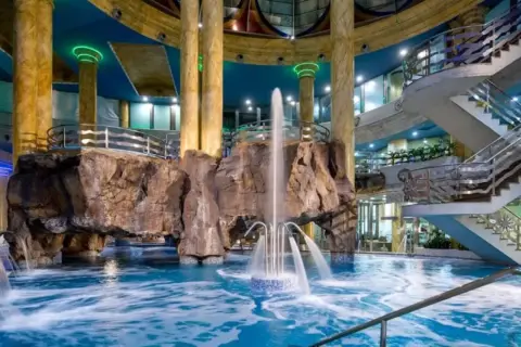 Interior de un balneario en la Comunidad Valenciana con piscina, cascadas, rocas artificiales y escaleras.