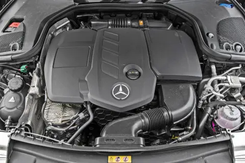 Silnik Mercedes-Benz E-Class. Widoczny czarny plastikowy dyfuzor, logo gwiazdy Mercedesa i elementy układu dolotowego.