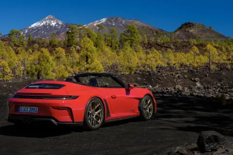 Czerwony kabriolet Porsche GT3 na tle gór i żółtych drzew. Czy to najładniejsze auto na świecie?
