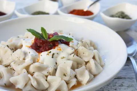 En skål med manti, små dumplings med yoghurt, tomatsås och mynta. Ett utsökt manti recept att prova!