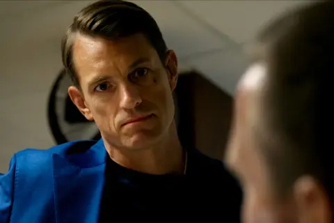 Joel Kinnaman i blå kavaj, intensiv blick mot någon i närbild. Ser ut som en scen från en ny serie.