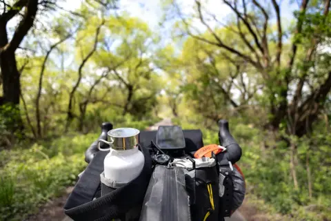 Widok z kierownicy roweru podczas bikepacking gravel. Biała butelka, nawigacja i torba podsiodłowa gotowe na przygodę.