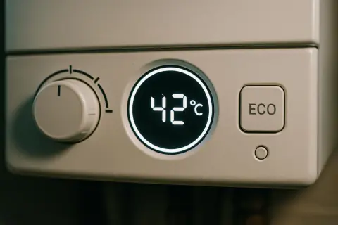 Wyświetlacz pieca kondensacyjnego pokazuje 42°C. Pokrętło regulacji i przycisk ECO sugerują, jak działa piec kondensacyjny, oszczędzając energię.