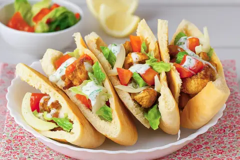 Cinco deliciosos panes de pita rellenos de pollo crujiente, lechuga, tomate y aderezo cremoso.