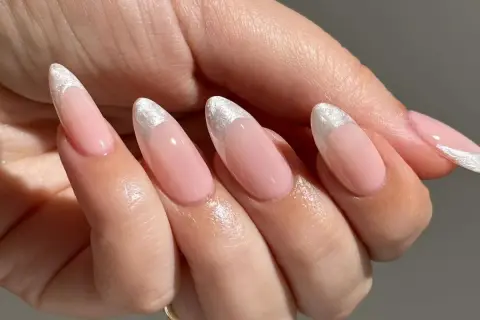 Delikatne, różowe paznokcie w stylu princess nails french z błyszczącym, srebrnym wykończeniem na końcówkach.