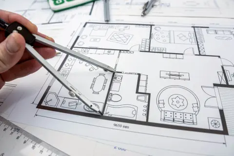 Rysunek techniczny mieszkania, cyrkiel w dłoni. Czy to próba wprowadzenia zmian w projekcie budowlanym bez zgody projektanta?