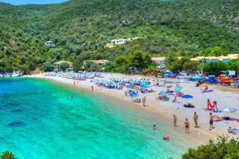 Piękna plaża z turkusową wodą, zielone wzgórza i domki w tle. To idealne miejsce na wakacje na Karaibach, wyspy zapraszają do odpoczynku.