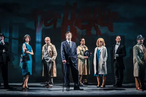 Szene aus dem alten Theaterhaus Stuttgart: Sieben Personen in Kostümen der 1960er Jahre stehen auf einer Bühne.