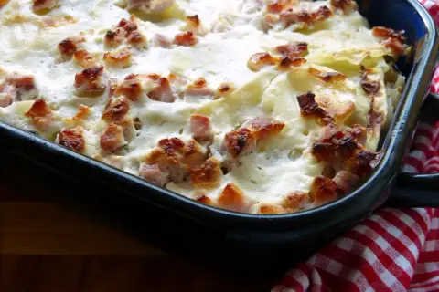 Ein köstlicher Bamberger Krautbraten in einer Auflaufform, überbacken mit cremiger Soße und knusprigen Speckwürfeln.