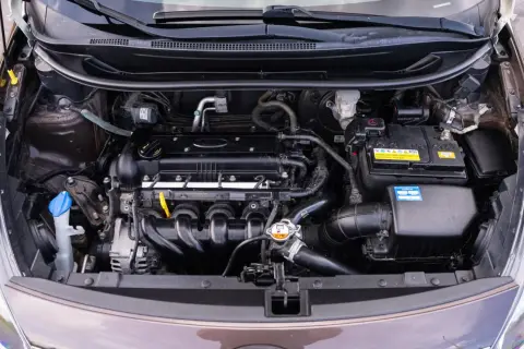 Silnik Kia Rio 3 z widocznym akumulatorem, przewodami i innymi elementami układu napędowego.