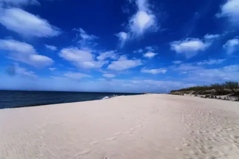Piękny, pusty piasek i błękitne niebo z chmurami. Idealne miejsce na wyjazd nad morze.