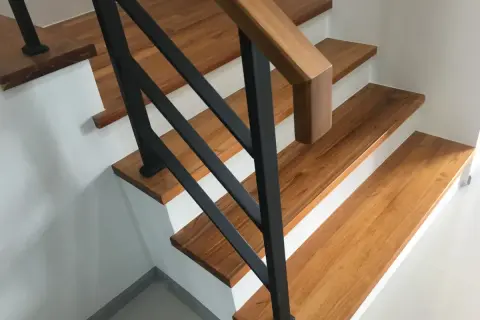 Moderne Treppen aus Holz mit schwarzem Geländer in einem Einfamilienhaus.