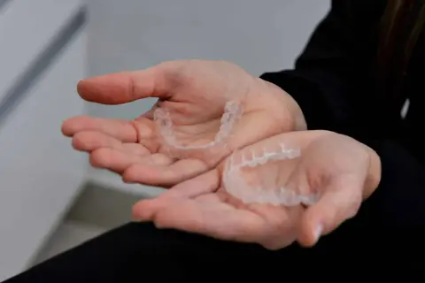 Mani che tengono bite trasparenti, utili per contrastare le mad apnee notturne.