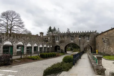 El Pazo de Coton, con su arquitectura de piedra y arcos, se alza bajo un cielo nublado, invitando a un paseo tranquilo.