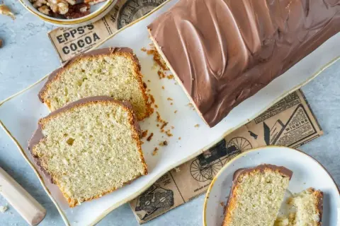 Saftiger Nusskuchen mit Schokoladenglasur, perfekt für Ihr nächstes nusskuchen rezept. Daneben liegen Walnüsse und ein Stück Kuchen.