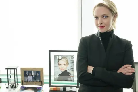 Amanda Seyfried som Elizabeth Holmes i "The Dropout", med armarna i kors och en tidning med hennes ansikte på.