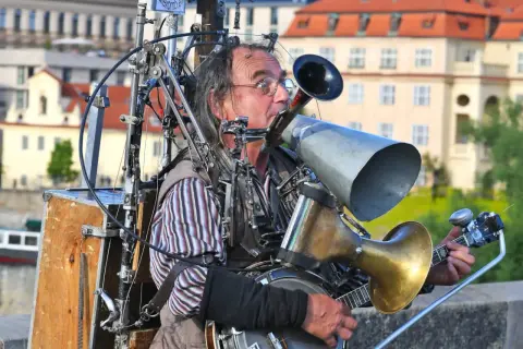 Ein Mann spielt auf einem selbstgebauten Blechblas-Instrument, das mit einem Banjo und vielen mechanischen Teilen verbunden ist.