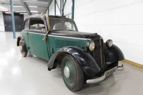 En grön och svart DKW med en spånkorgsdetalj på taket, står i ett garage.