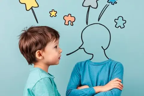 Chłopiec wpatruje się w rysunek głowy z bańką myśli. Terapia komunikacji autyzm.