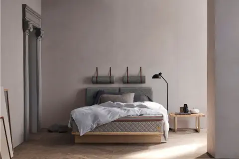 Stilvolles Schlafzimmer mit grauem Bett, minimalistischer Deko und warmem Holzboden. Tolle Schlafzimmer Ideen für Ruhe.