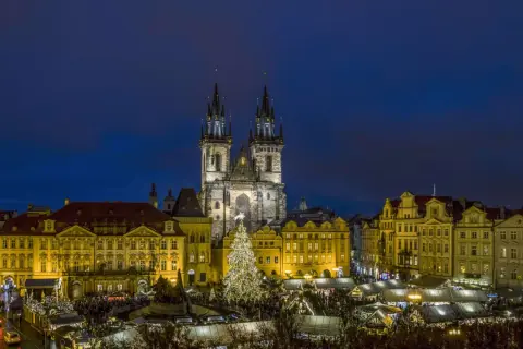 Prag im Winter: Der beleuchtete Weihnachtsbaum auf dem Altstädter Ring, umgeben von Ständen und der Teynkirche, erstrahlt in der Dämmerung.