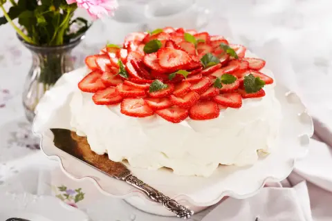 En vacker jordgubbstårta med vispgrädde och färska jordgubbar, perfekt för ett sommarfika. Ett enkelt jordgubbstårta recept att prova!