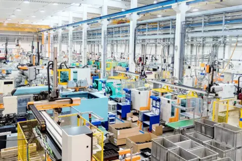 Nowoczesna hala produkcyjna z liniami maszyn, robotami i taśmociągami. Efektywne zarządzanie produkcją w akcji.