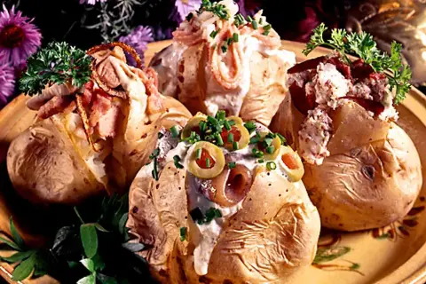 Fyra läckra bakade potatisar med olika fyllningar, toppade med gräddfil, bacon, oliver och örter. En festlig och mättande rätt!