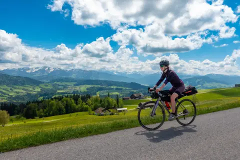 Frau auf Radtour durch Deutschland, genießt die Aussicht auf grüne Hügel und Berge. Perfekt für eine 3 Tage Radtour Deutschland.