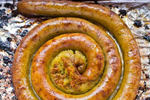 Złocista kiszka ziemniaczana zwinięta w spiralę na folii aluminiowej.